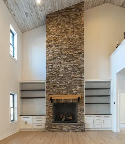 Tall brown stone fireplace with shelves on both sides